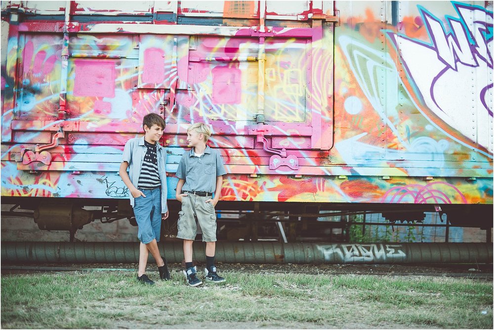 Two kids standing side by side in front of a graffiti wall during a family session.