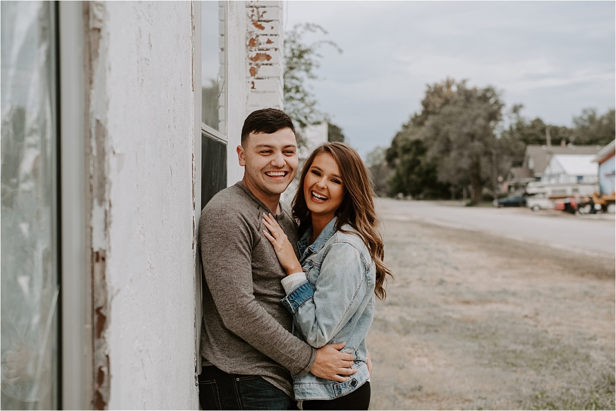 Portrait of engaged couple laughing at the camera next to abandoned building