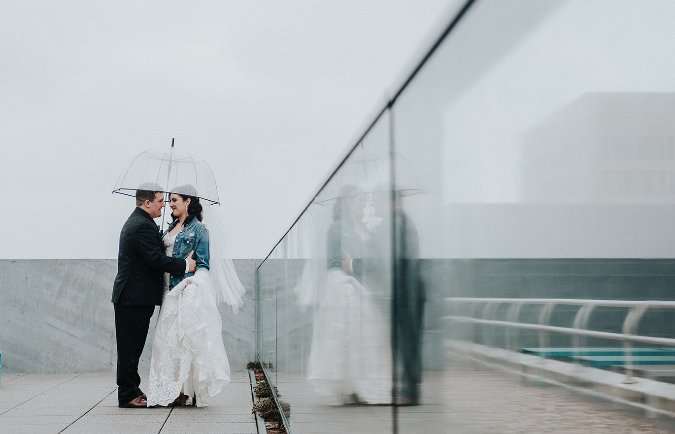 bride groom kissing in rain on rooftop